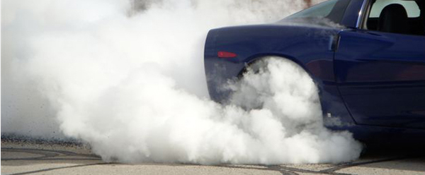 A Corvette produces a plume of smoke from its rear tires.