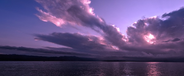 A partly cloudy sky tinted violet.